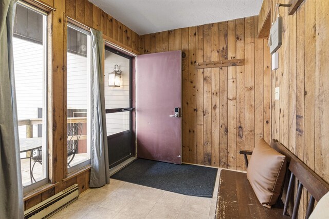 tiled foyer featuring a baseboard heating unit, wooden walls, and a wealth of natural light