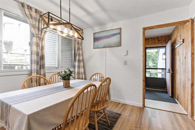 dining room featuring light wood-type flooring and wood walls