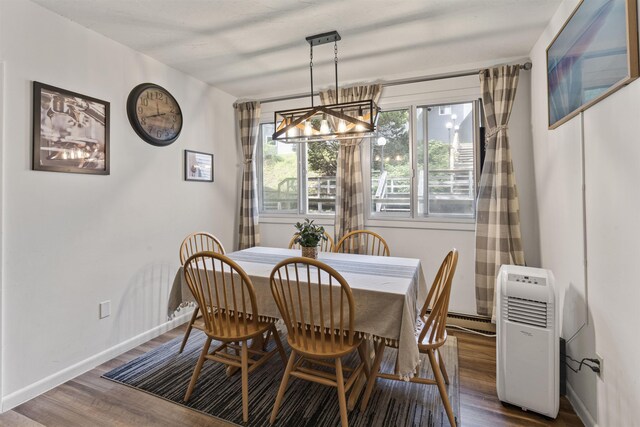 dining room with a notable chandelier, baseboard heating, and dark wood-type flooring