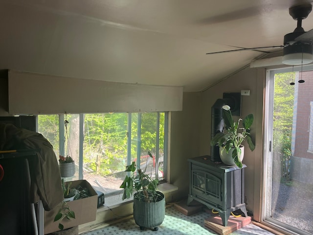 interior space with ceiling fan, a wood stove, and lofted ceiling