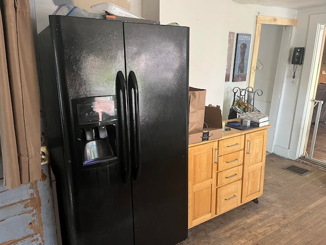 kitchen with black fridge, light brown cabinetry, and dark hardwood / wood-style floors