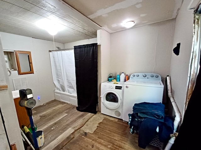 clothes washing area with hardwood / wood-style flooring and washer and dryer