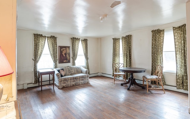 sitting room featuring baseboard heating, a wealth of natural light, and dark hardwood / wood-style flooring