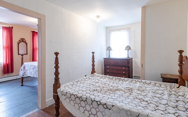 bedroom featuring wood-type flooring and a baseboard heating unit