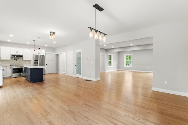 kitchen featuring open floor plan, light wood-style flooring, appliances with stainless steel finishes, and light countertops