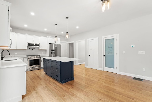 kitchen featuring visible vents, light countertops, white cabinets, stainless steel appliances, and a sink