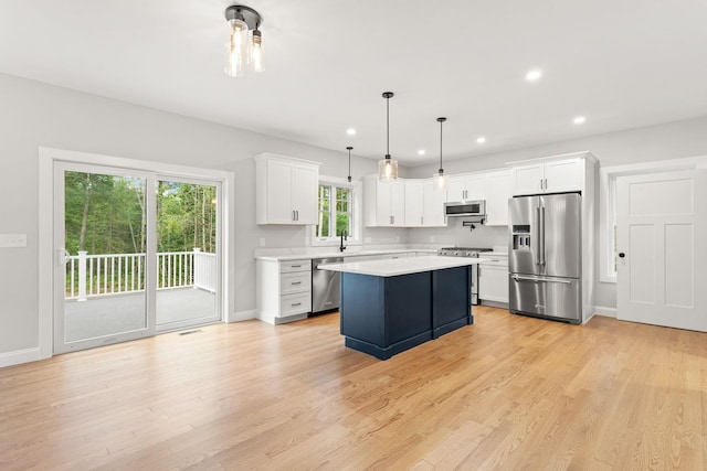 kitchen with a kitchen island, a sink, light countertops, light wood-style floors, and appliances with stainless steel finishes