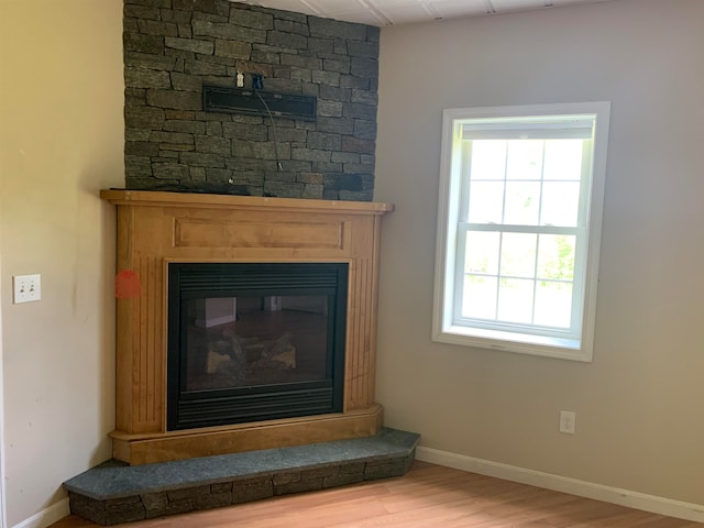 interior details featuring a glass covered fireplace, wood finished floors, and baseboards