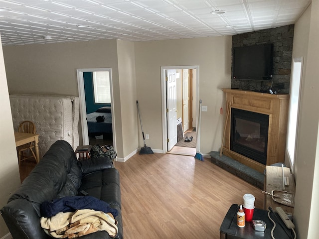 living room featuring a glass covered fireplace, light wood-style flooring, and baseboards