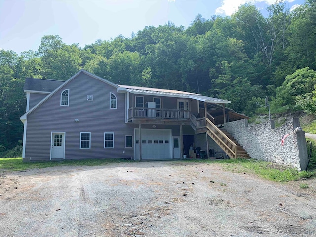 view of front of property with stairs, a porch, a garage, and dirt driveway