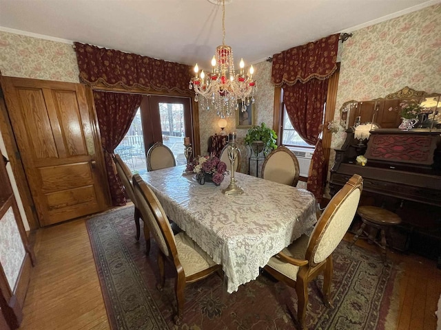 dining space with a wealth of natural light, wallpapered walls, an inviting chandelier, and wood finished floors