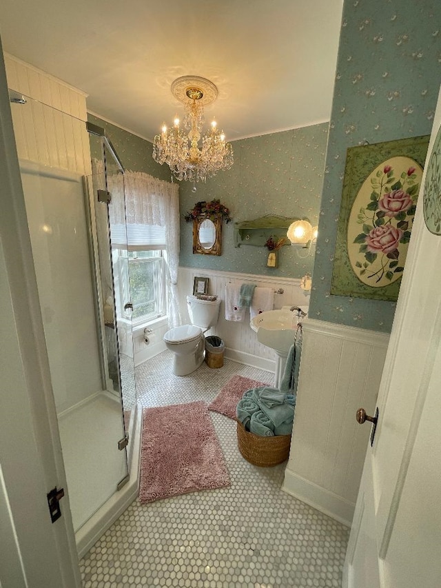 full bath featuring wallpapered walls, a wainscoted wall, toilet, a stall shower, and a notable chandelier