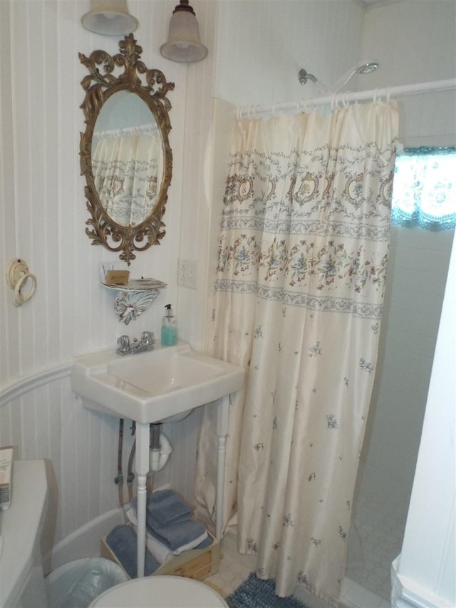 bathroom with curtained shower, toilet, and a sink