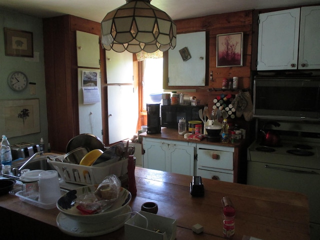 kitchen featuring decorative light fixtures, white electric stove, and white cabinets