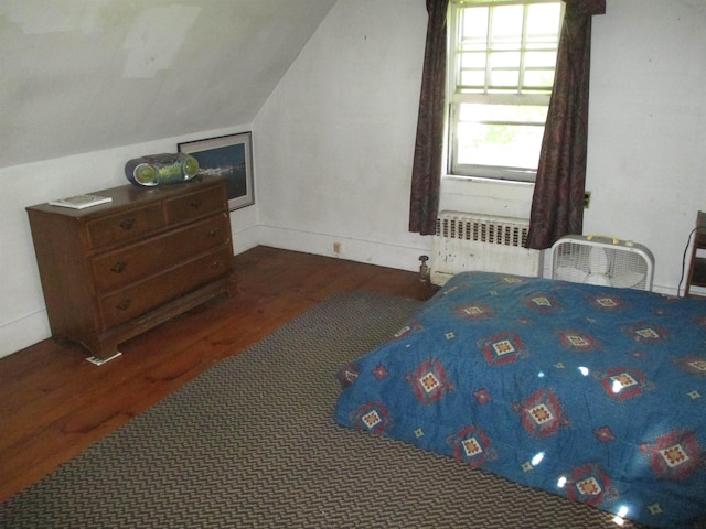 bedroom with vaulted ceiling, dark wood-type flooring, and radiator