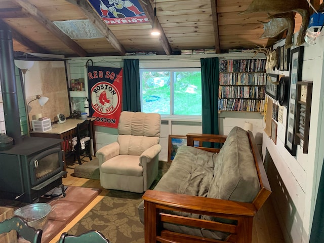 sitting room with beamed ceiling, a wood stove, wooden ceiling, and wood finished floors