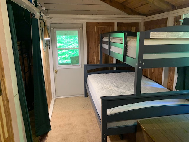 bedroom with wooden walls, vaulted ceiling, and carpet floors