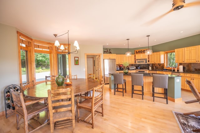 dining space with light hardwood / wood-style floors and an inviting chandelier