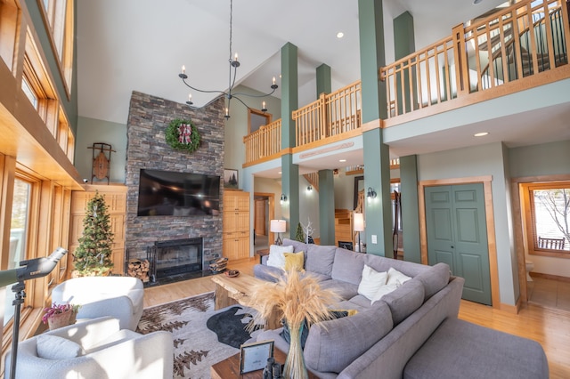 living room featuring a stone fireplace, a towering ceiling, and light hardwood / wood-style flooring