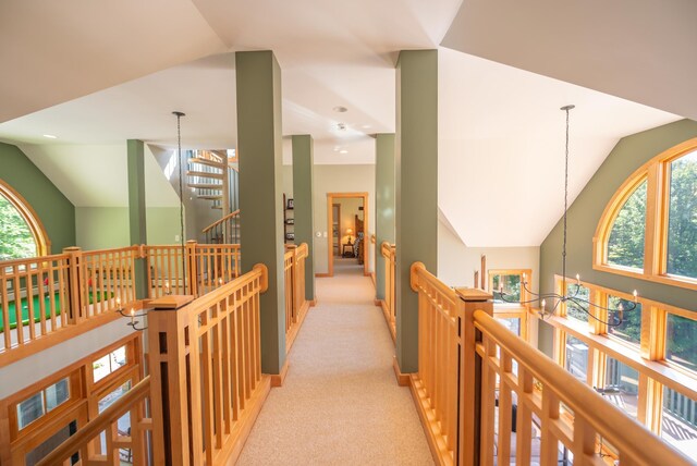 corridor with light colored carpet, lofted ceiling, and a notable chandelier