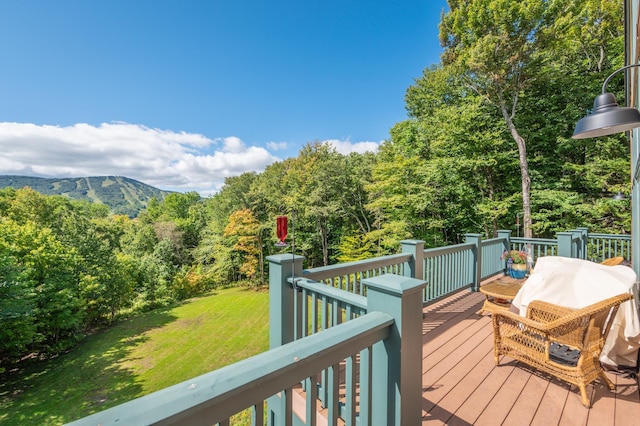 wooden deck featuring a mountain view and a yard