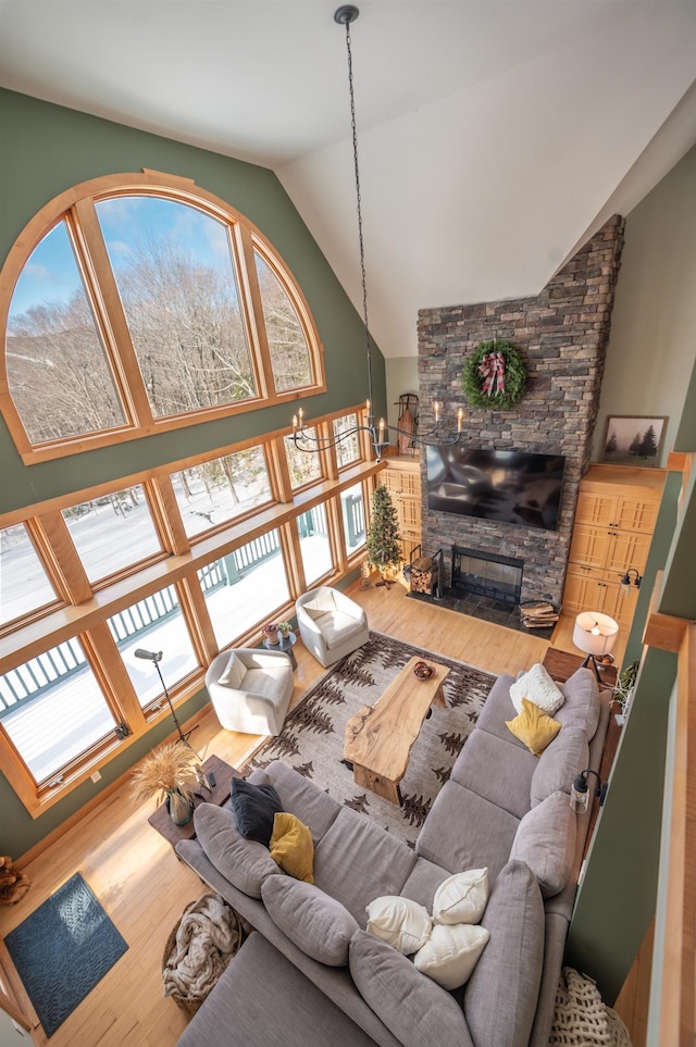 living room featuring a stone fireplace, hardwood / wood-style floors, and lofted ceiling