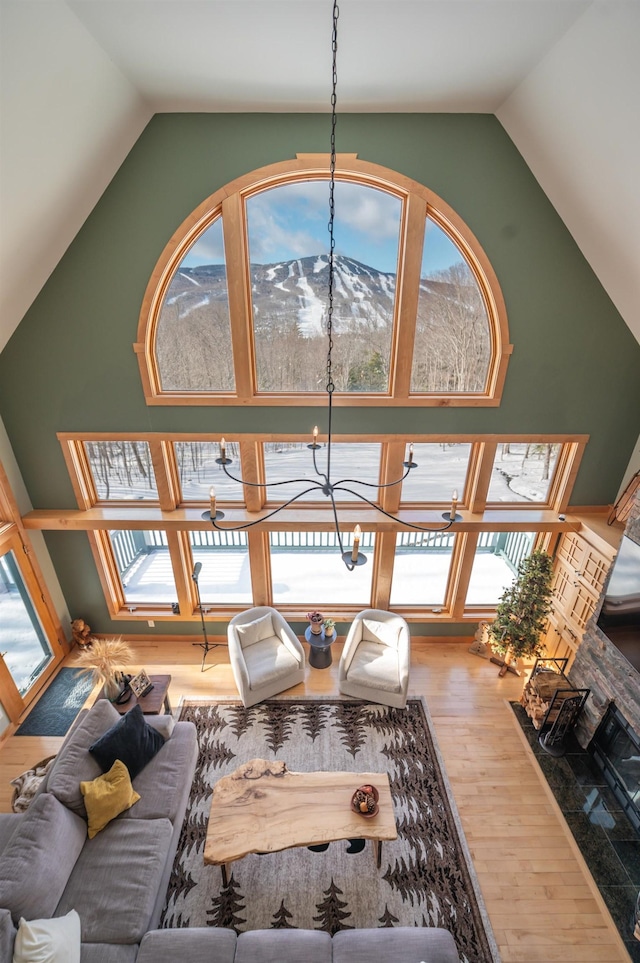 living room with a mountain view, high vaulted ceiling, hardwood / wood-style flooring, and an inviting chandelier