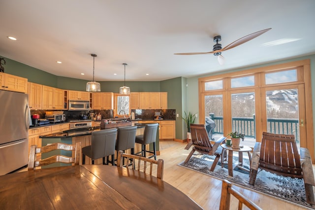 dining space with ceiling fan and light wood-type flooring