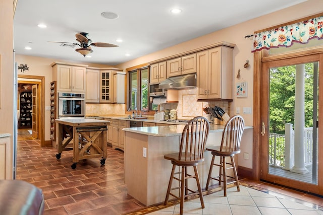 kitchen featuring decorative backsplash, stainless steel oven, a wealth of natural light, and under cabinet range hood