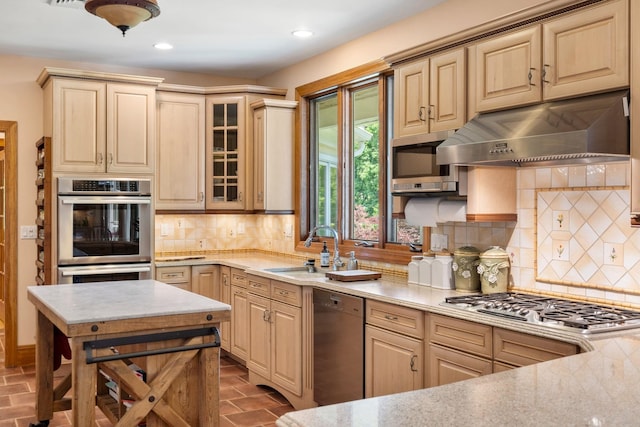 kitchen featuring a sink, decorative backsplash, glass insert cabinets, appliances with stainless steel finishes, and under cabinet range hood