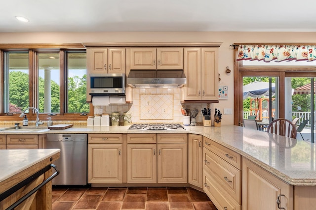 kitchen featuring a sink, light brown cabinetry, under cabinet range hood, and stainless steel appliances