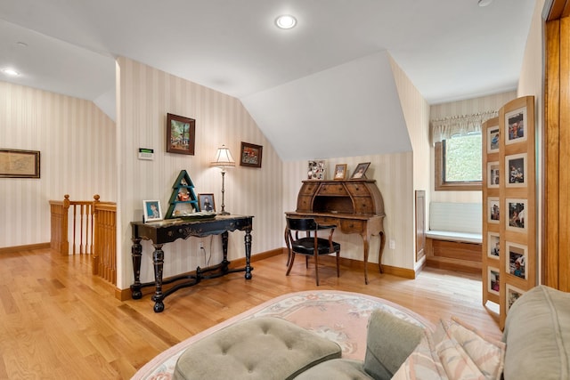 living area featuring wallpapered walls, lofted ceiling, and wood finished floors