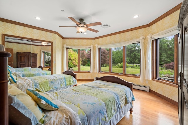 bedroom with light wood-style floors, crown molding, wallpapered walls, a baseboard radiator, and baseboards