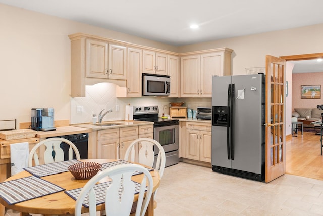 kitchen featuring a sink, stainless steel appliances, light countertops, cream cabinets, and backsplash