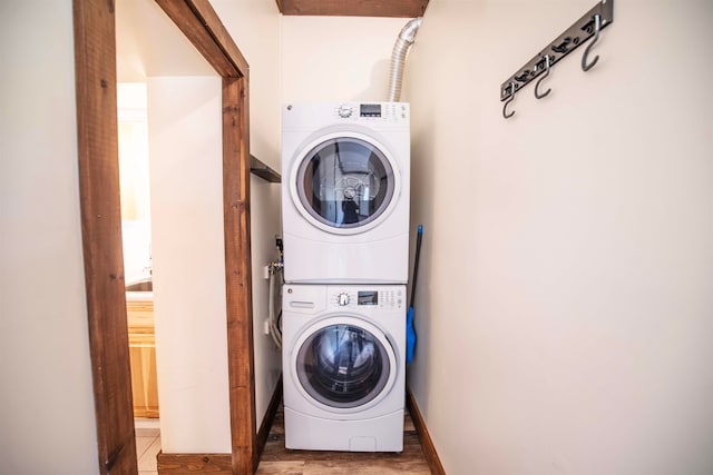 clothes washing area featuring dark tile patterned flooring and stacked washer / dryer