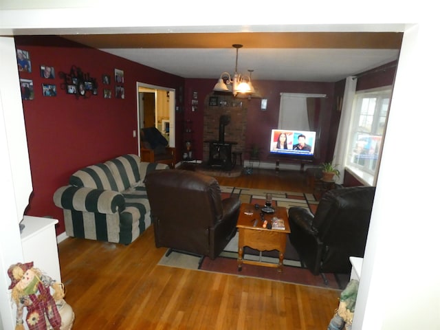 living room featuring hardwood / wood-style floors, a notable chandelier, and a wood stove