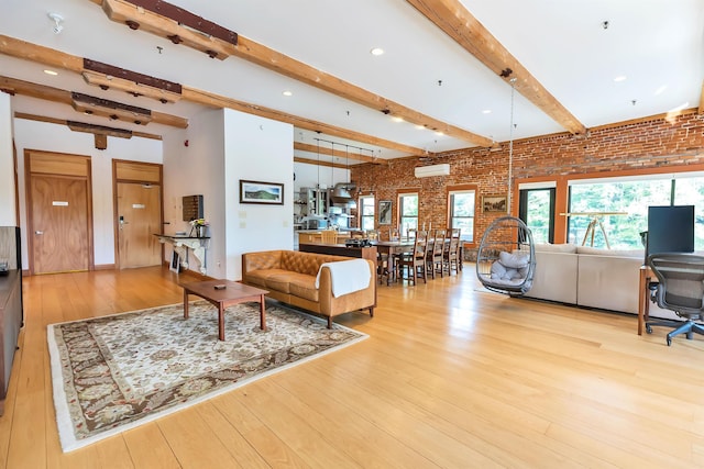 living room with an AC wall unit, light hardwood / wood-style flooring, beamed ceiling, and brick wall