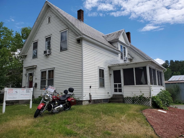 back of house featuring a lawn and a sunroom