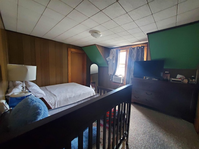 bedroom featuring carpet flooring and wood walls