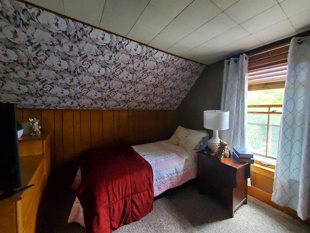 bedroom featuring carpet flooring, wooden walls, and lofted ceiling