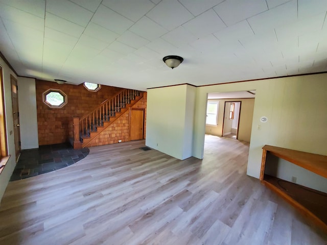 unfurnished living room featuring light wood-type flooring and ornamental molding