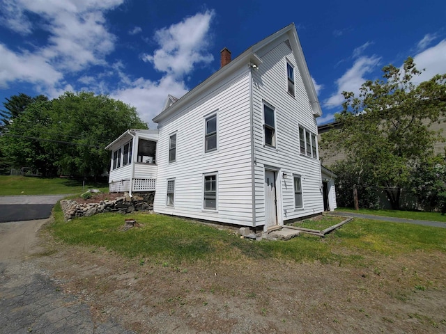 view of side of property with a lawn and a sunroom