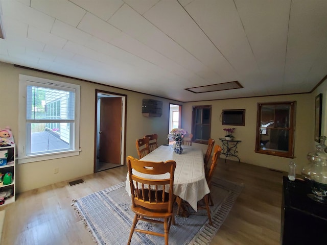 dining space with a wealth of natural light, crown molding, and wood-type flooring