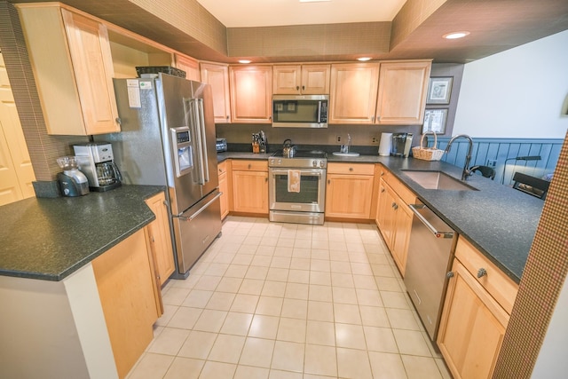 kitchen with kitchen peninsula, sink, light brown cabinetry, and appliances with stainless steel finishes