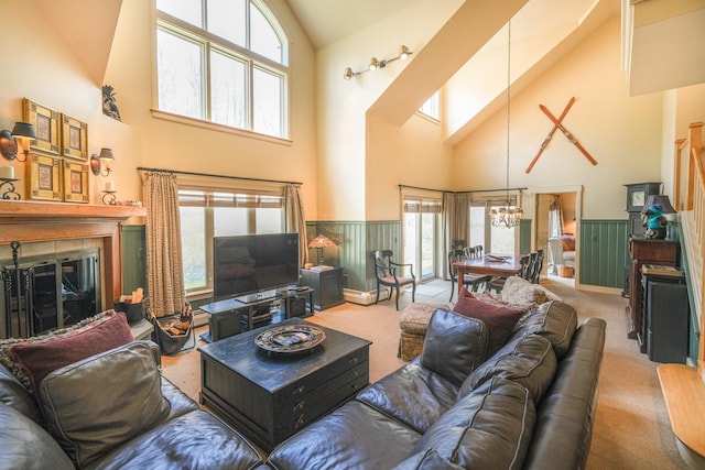 carpeted living room featuring a notable chandelier, a high ceiling, and a tiled fireplace