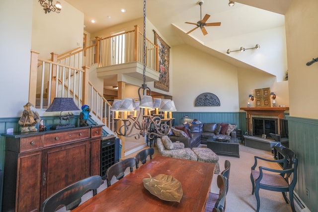 carpeted living room with ceiling fan with notable chandelier, a towering ceiling, and baseboard heating