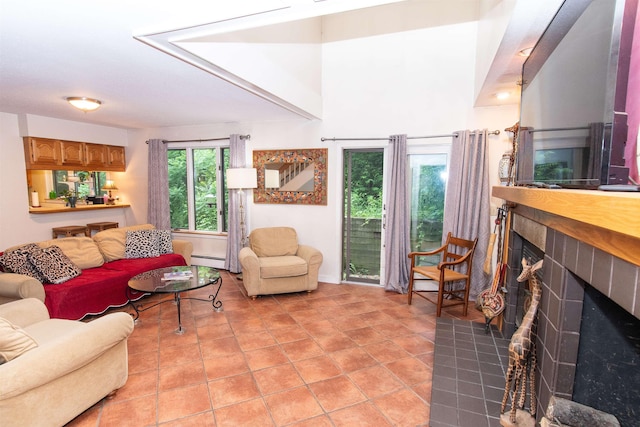 living room featuring a tiled fireplace, light tile patterned flooring, and baseboard heating