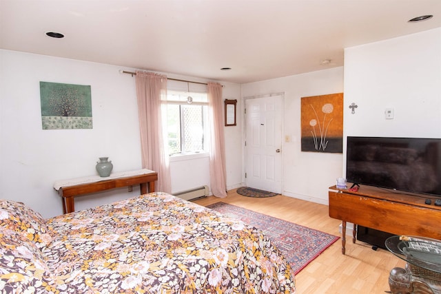 bedroom featuring hardwood / wood-style flooring and a baseboard heating unit