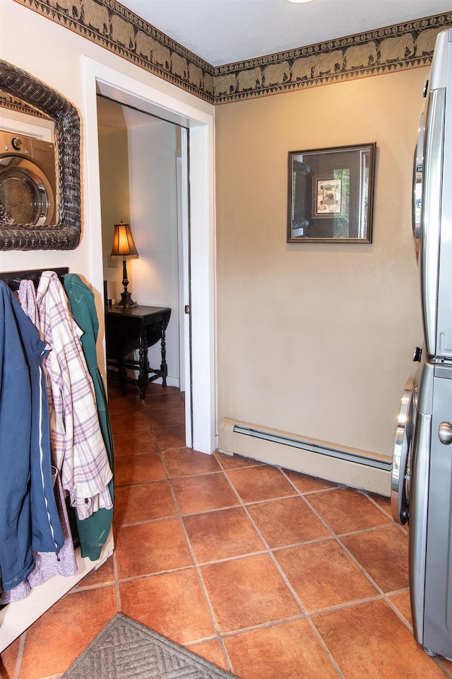 hallway featuring tile patterned flooring, a baseboard heating unit, and stacked washer and clothes dryer