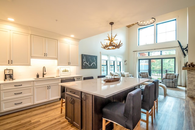 kitchen with light wood finished floors, a breakfast bar, light countertops, an inviting chandelier, and a sink